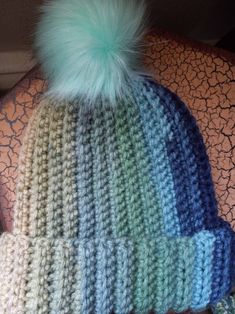 a knitted hat with a green pom - pom on top of it