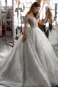 a woman in a white wedding dress standing next to a mirror