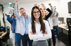 a group of people standing around each other in an office with arms up and smiling