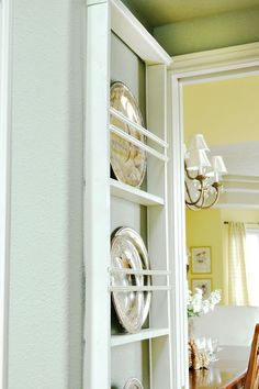 a white shelf with plates on it next to a dining room table