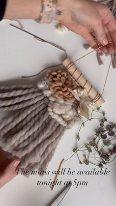 two hands are working with yarn on a table