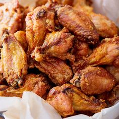 a pile of chicken wings sitting on top of a white paper bag in a basket