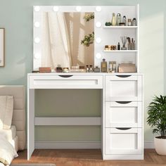 a white vanity with lights on it in a room next to a bed and potted plant