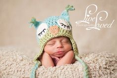 a newborn baby wearing a crocheted owl hat and sleeping on top of a blanket