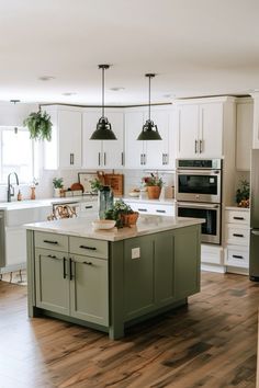 a kitchen with white cabinets and green island