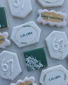 some decorated cookies are sitting on a white tablecloth with green and gold trimmings