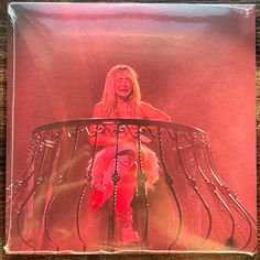 a woman sitting on top of a metal table in front of a pink background with chains