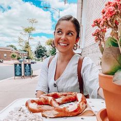 a woman sitting at a table with some doughnuts in front of her and a potted plant