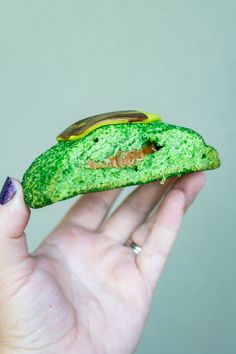 a hand holding a piece of food with green icing on it's side