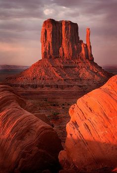 the rock formations in the desert are orange and red as the sun sets behind them