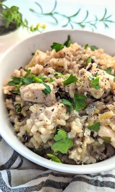 a white bowl filled with rice and meat on top of a blue and white table cloth