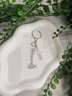 a white plate with a keychain on top of it next to some green plants