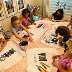 a group of children sitting around a table with art supplies