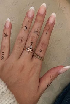 a woman's hand with two different tattoos on her fingers and an arrow ring