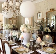 a dining room table set with white flowers and place settings for four people to sit at