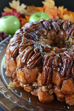 a bundt cake covered in pecans and caramel on a glass platter