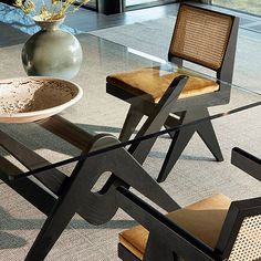 a glass table with two chairs and a vase