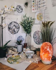 a table topped with vases filled with flowers and plants next to pictures on the wall