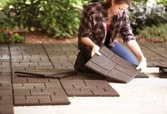 a woman kneeling down on the ground with a piece of brick in front of her