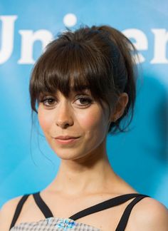 a close up of a person wearing a dress and hair in a bun with bangs