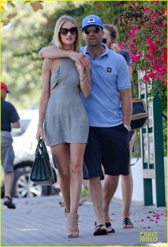 a man and woman are walking down the street with their arms wrapped around each other