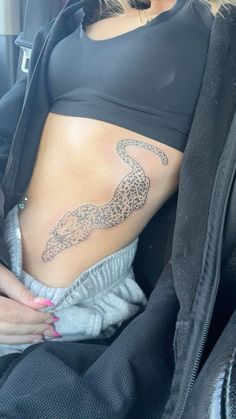 a woman is sitting in the back seat of a car with a tattoo on her stomach