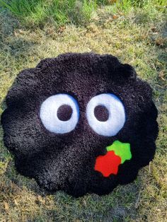 a black object with googly eyes and a holly berry on it's nose