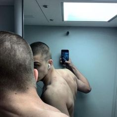 a man taking a selfie in front of a mirror with his cell phone to his ear