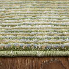 a close up view of a rug on a wooden floor with green and blue stripes