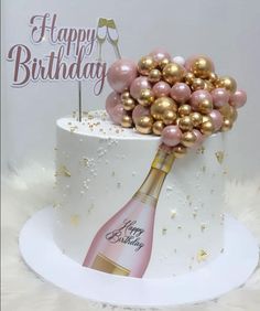 a birthday cake decorated with pink and gold balloons, champagne bottle and happy birthday sign