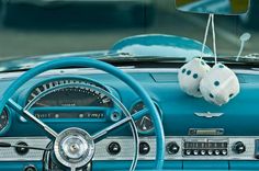 two stuffed animals are hanging from the dash board of a classic car's dashboard