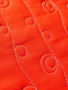 an orange piece of fabric with white stitching and circles on the bottom half of it