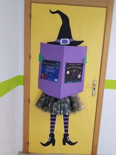 a door decorated with a purple box and witch's hat on it, sitting in front of a yellow wall