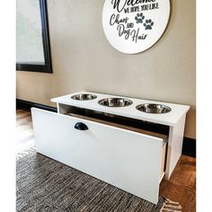 a white cabinet with two bowls on it in front of a sign that says welcome to the dog house