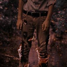 a man is standing in the rain with his boots on and water splashing all over him