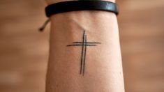 a person with a cross tattoo on their arm