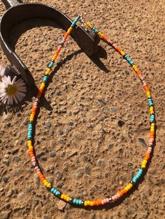 a colorful beaded necklace and flower on the ground