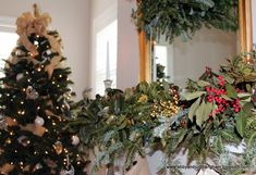 a christmas tree is decorated with greenery and other holiday decorations in front of a mirror