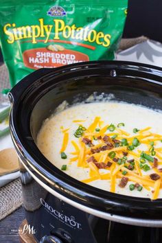 a crock pot filled with soup and cheese next to a bag of potato chips