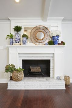 a living room with a fire place and potted plants on top of the fireplace