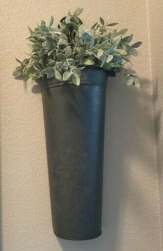 there is a black vase with green plants in it hanging on the wall next to a door