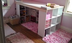 a room with pink walls and carpeted flooring on the floor, along with a white book shelf filled with books