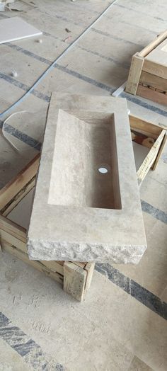 a concrete sink sitting on top of wooden pallets in an unfinished room with construction materials around it