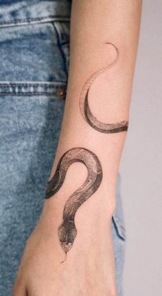 a woman's arm with a snake tattoo on her left wrist and the word question written in cursive writing