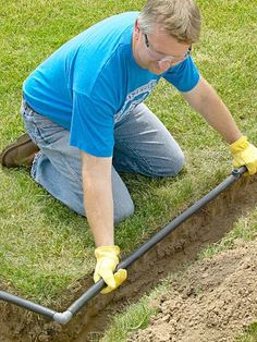 a man laying on the ground in front of a hole with a pipe attached to it