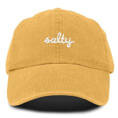 Embrace the laid-back charm of coastal living with our Salty baseball cap. Crafted from 100% cotton, our 6-panel low-crown dad cap combines comfort with effortless style. Whether you're strolling along the boardwalk, lounging on the sand, or simply running errands under the sun, our cap promises a blend of functionality and fashion that suits every beach lover's lifestyle. Measuring 11 inches in length, this unstructured cap features a fabric strap closure with a metal buckle, ensuring a secure Beach Beige Baseball Cap, Trendy 5-panel Baseball Cap For Beach, Yellow Baseball Cap Dad Hat, Gold Casual Baseball Cap, One Size, Cheap 5-panel Baseball Cap For Beach, Cool Dad Hats, Dark Men, Beach Attire, Cozy Hat