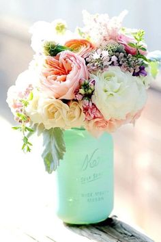 a vase filled with lots of flowers on top of a wooden table next to a cell phone