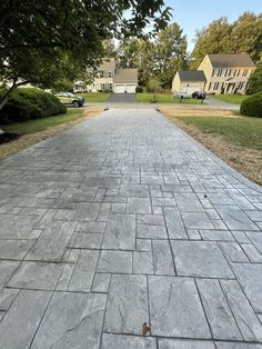 a brick walkway in the middle of a residential area with trees and houses behind it