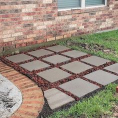 a brick walkway in front of a house with grass and bricks on the ground next to it