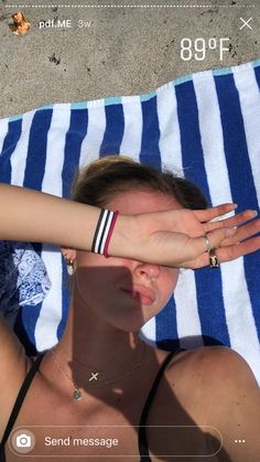 a woman laying on top of a blue and white towel next to a person with their hand over her face